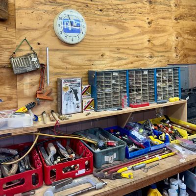 Sale Photo Thumbnail #15: Workshop scene featuring a PPG wall clock, blue plastic multi-drawer parts organizers, a Speedway Series paint spray gun in box, crates of hand tools, and pry bars.