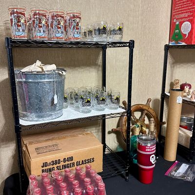 Sale Photo Thumbnail #37: Black wire shelving unit displayed with collectible drinking glasses, a galvanized bucket, and a sealed case of red aluminum Coca-Cola bottles.