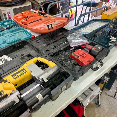 Sale Photo Thumbnail #20: Collection of used power tools in hard plastic carrying cases, including a DeWalt portable band saw, cordless drills, and a hammer drill.
