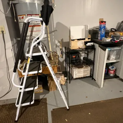 Sale Photo Thumbnail #48: A modern white and black four-step folding stepladder, shown in a utility area alongside shelving and household items.