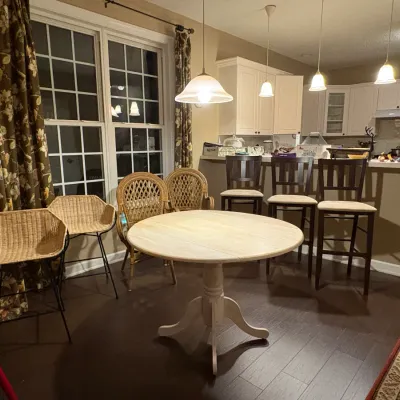 Sale Photo Thumbnail #34: Light wood pedestal dining table surrounded by a assortment of seating, including woven wicker chairs and dark wooden barstools.