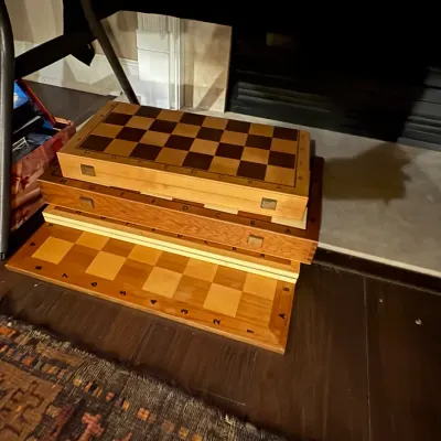 Sale Photo Thumbnail #32: Stack of folding wooden game boards, featuring checkered chess and backgammon designs with algebraic notation.