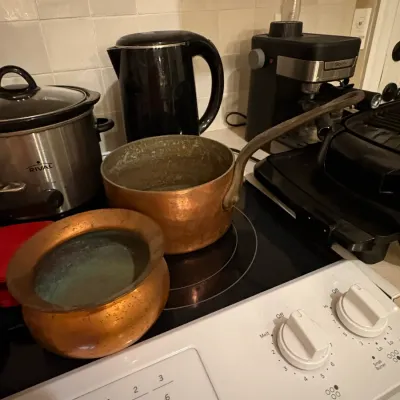 Sale Photo Thumbnail #45: Pair of vintage copper cooking vessels, including a long-handled saucepan and a rounded pot, shown alongside modern kitchen appliances.