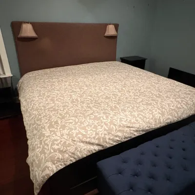 Sale Photo Thumbnail #51: Contemporary king-size bed frame featuring a brown upholstered headboard with built-in reading lamps, paired with a blue tufted ottoman bench at the foot.