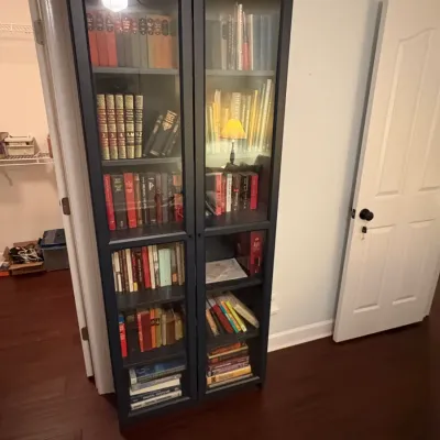 Sale Photo Thumbnail #64:  dark navy glass-door bookcase filled with various books and decorative accents.