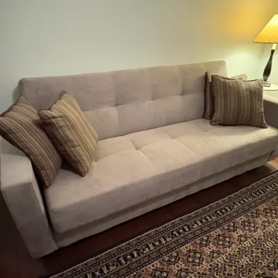 Sale Photo Thumbnail #71: Contemporary beige tufted fabric sofa accompanied by four striped throw pillows, displayed next to a table lamp and patterned area rug.