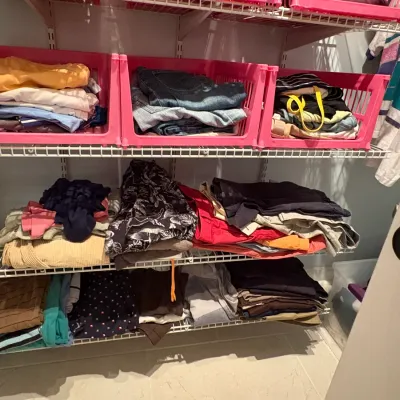 Sale Photo Thumbnail #58: Closet organization shelving unit filled with stacks of folded casual clothing and brightly colored pink plastic storage crates.