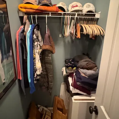 Sale Photo Thumbnail #75: Small closet filled with assorted clothing, baseball caps, folded textiles, and hangers.
