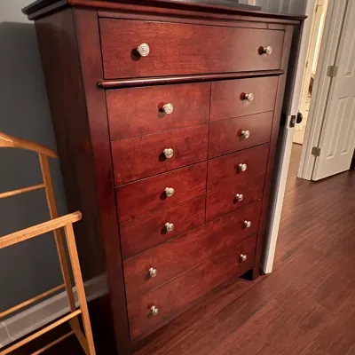 Sale Photo Thumbnail #55: Tall cherry wood chest of drawers featuring brushed metal round knobs and a multi-drawer configuration. Shown alongside a natural wood suit valet stand.