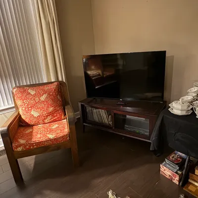Sale Photo Thumbnail #25: Wooden armchair with patterned red upholstery shown beside a dark wood media console topped with a flat-screen television.