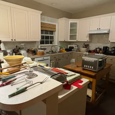 Sale Photo Thumbnail #36: Selection of vintage kitchenware laid out on a kitchen island, including rolling pins, utensils with painted wooden handles, a mixing bowl, and small appliances.