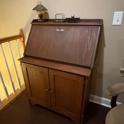 Sale Photo Thumbnail #62: Vintage dark wood slant-front  desk with a lower two-door storage cabinet and decorative keyhole hardware.