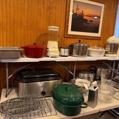 Sale Photo Thumbnail #107: Collection of kitchen appliances and cookware, including a Cuisinart blender, Sunbeam stand mixer, red and green enamel Dutch ovens, stainless steel pots, and a Hamilton Beach roaster oven.