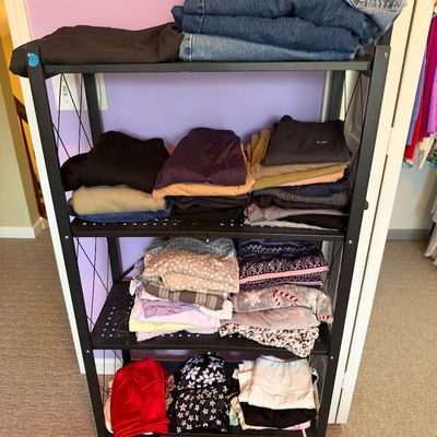 Sale Photo Thumbnail #57: Black metal four-tier rolling shelf unit organized with neat stacks of folded casual clothing and denim jeans.