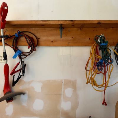 Sale Photo Thumbnail #16: Red electric string trimmer hanging alongside various jumper cables and extension cords mounted below a wooden shelf.