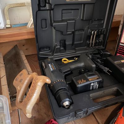 Sale Photo Thumbnail #9: Craftsman Industrial 14.4V cordless drill/driver set in its original hard plastic case with a battery charger, shown alongside a traditional wooden hand saw.