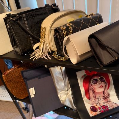 Sale Photo Thumbnail #23: Collection of women's handbags and evening clutches displayed on a black wire shelving unit, featuring faux-crocodile, quilted leatherette, and graphic designs.