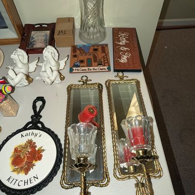 Sale Photo Thumbnail #70: Assortment of vintage home decor items including a pair of brass and glass mirrored wall sconces, cherub figurines, a ceramic trivet, and a clear glass vase.