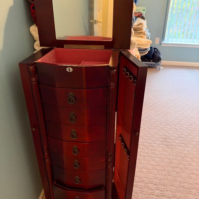 Sale Photo Thumbnail #28: Traditional cherry-finish standing jewelry armoire featuring a flip-top mirror, felt-lined compartments, side necklace doors, and multiple drawers.