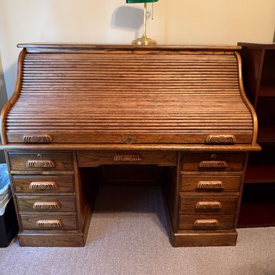 Sale Photo Thumbnail #42: Traditional oak roll-top desk with carved handles and double pedestals, topped with a brass banker's lamp with a green shade.