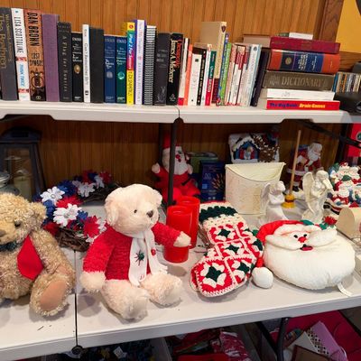 Sale Photo Thumbnail #106: Collection of holiday decorations, teddy bears, and hardcover books arranged on folding tables.