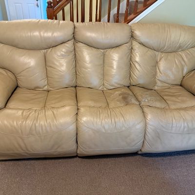 Sale Photo Thumbnail #37: Contemporary beige leather reclining sofa with plush back cushions and padded armrests, showing significant wear and damage on the seat cushions.