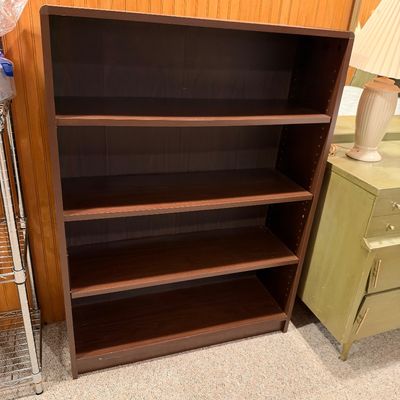 Sale Photo Thumbnail #21: Dark brown laminate four-shelf bookcase with adjustable shelving, showing light wear along the bottom edge.