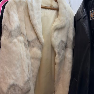 Sale Photo Thumbnail #58: Vintage white fur jacket featuring subtle gray chevron patterning, wide lapels, and a cream-colored lining, displayed on a wooden hanger.