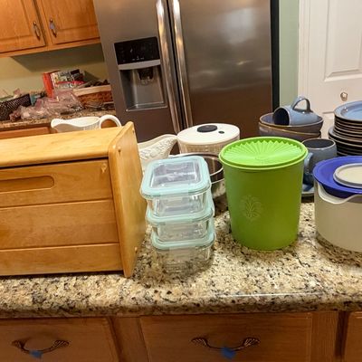 Sale Photo Thumbnail #85: Collection of kitchen items including a wooden roll-top bread box, vintage green Tupperware Servalier canister, glass food storage containers, and blue stoneware dishware set.