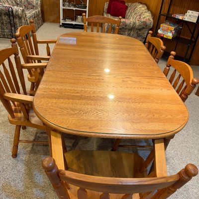 Sale Photo Thumbnail #110: Traditional oak dining table with protective glass top, accompanied by six matching spindle-back wooden chairs in good condition.