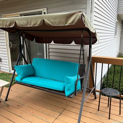Sale Photo Thumbnail #91: Outdoor patio porch swing with a metal frame, overhead fabric canopy, bright turquoise cushions, and two matching accent pillows.