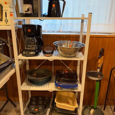 Sale Photo Thumbnail #22: White metal four-tier rolling shelf unit displaying kitchen small appliances and cookware, including coffee makers, stainless steel mixing bowls, glass baking dishes, and muffin pans.