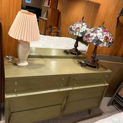 Sale Photo Thumbnail #94: Mid-century modern olive green dresser with attached mirror, displayed with a pleated fabric shade lamp and Tiffany-style floral leaded glass table lamp.