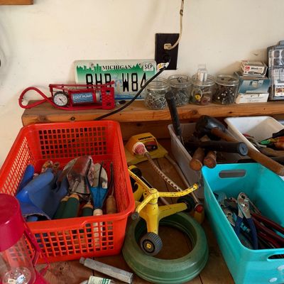 Sale Photo Thumbnail #14: Workshop shelf and workbench filled with various lawn care tools, hand tools, lawn sprinklers, and plastic storage caddies.