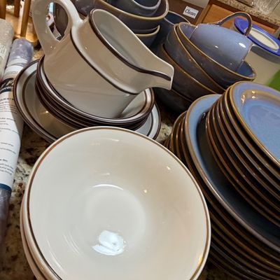 Sale Photo Thumbnail #81: Large collection of vintage mid-century stoneware dinnerware, featuring off-white and blue pieces with brown band trim, including plates, bowls, cups, and a gravy boat.