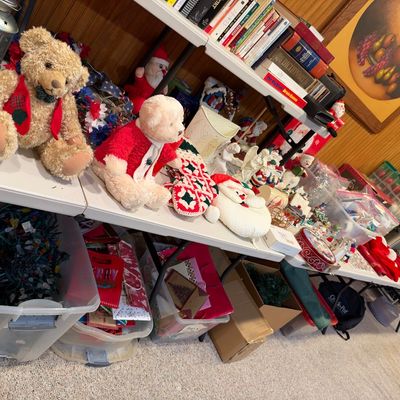 Sale Photo Thumbnail #105: Collection of plush teddy bears, Christmas decorations, and various household items displayed on folding tables and in storage bins.
