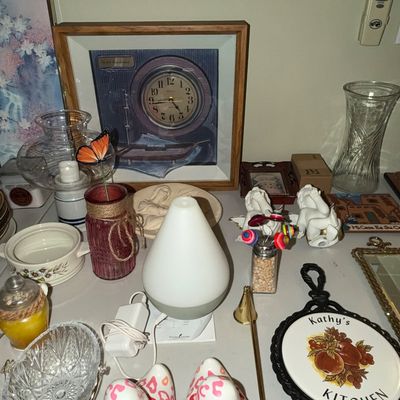 Sale Photo Thumbnail #72: Collection of home decor items featuring a teardrop-shaped essential oil diffuser, a pair of leopard-print ceramic ducks, framed artwork, and various glassware.