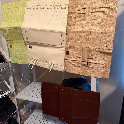 Sale Photo Thumbnail #25: Assortment of folding faux-alligator and leather jewelry organizers in various colors, displayed on a metal shelf unit.