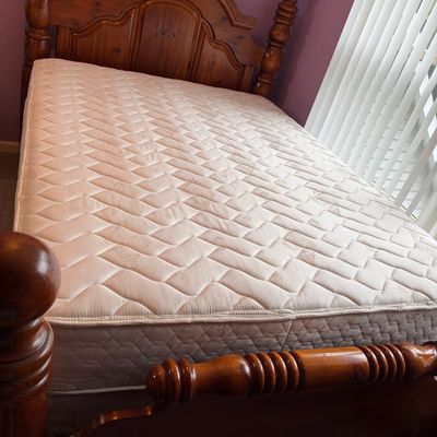 Sale Photo Thumbnail #50: Traditional wooden four-poster bed frame featuring turned finials and an arched headboard, complete with a quilted mattress.