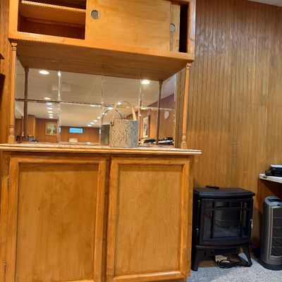Sale Photo Thumbnail #96: Mid-century wooden hutch featuring a mirrored backsplash, upper sliding cabinet doors, and lower storage cabinets, alongside a compact electric stove heater.
