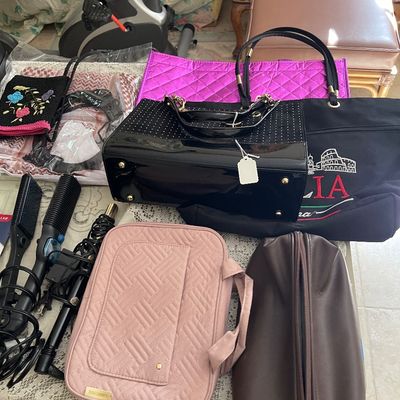 An assortment of women's accessories and hair styling tools, including a black studded tote bag, pink quilted travel case, and...