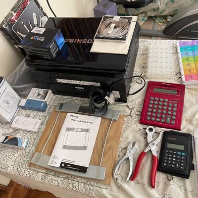 Collection of household office electronics and personal items, including a Toshiba laptop, HoMedics digital scale, calculators, hole...