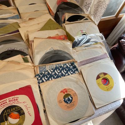 Large collection of vintage 45 RPM vinyl records in paper sleeves, featuring artists such as Eric Clapton, Roberta Flack, and Smokey...