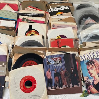 Large collection of vintage 45 RPM vinyl records in paper sleeves, including singles by Kool & The Gang, Madonna, and various labels.