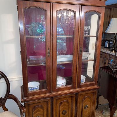 Traditional dark wood china cabinet with arched bonnet top, glass display doors, and lower storage cabinets with brass hardware.