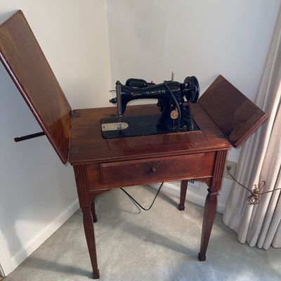 Vintage Singer electric sewing machine built into a wooden drop-leaf cabinet with a single drawer.