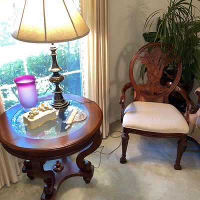 Traditional mahogany armchair with carved wheat-sheaf splat back and ball-and-claw feet, positioned beside a glass-top round end table...