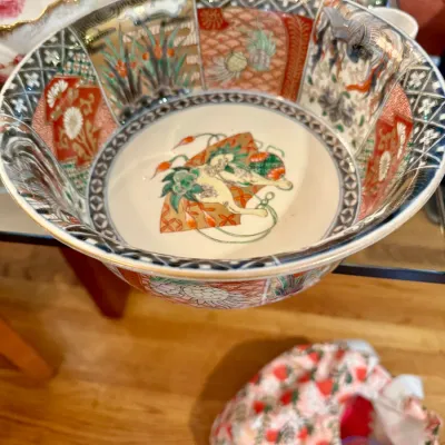 Intricately hand-painted Japanese Imari porcelain serving bowl, featuring vibrant polychrome panels, gilded accents, and geometric borders.