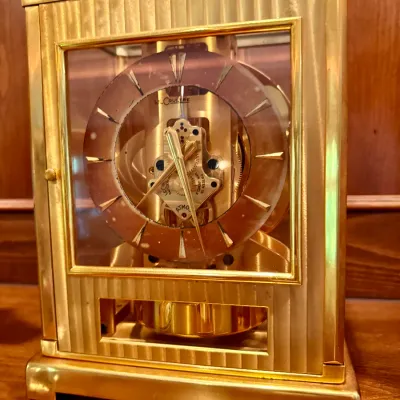 Vintage Jaeger-LeCoultre Atmos clock featuring a brass and glass case with a fluted facade and 15-jewel Swiss movement.