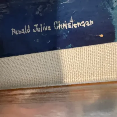 Close-up of an artist signature reading "Ronald Julius Christensen" on a framed blue oil painting.